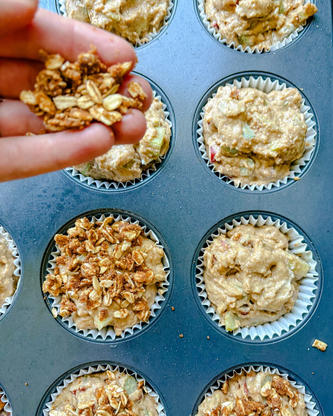 putting crumble topping on rhubarb muffins